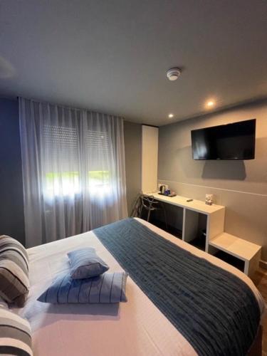 a bedroom with a large bed and a television at Hôtel Logis Restaurant La Fontaine in Mantry