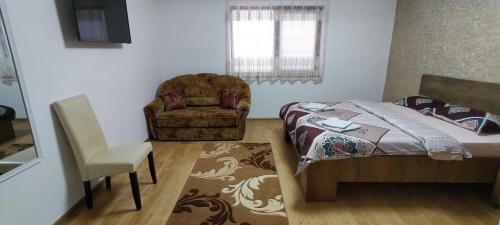 ein Schlafzimmer mit einem Bett und einem Stuhl in einem Zimmer in der Unterkunft Casa Luminița in Eşelniţa