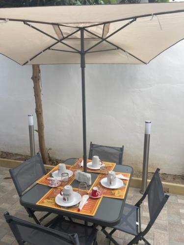 una mesa con sillas y una sombrilla con platos y tazas en Dimora Nonna Ada, en Aradeo