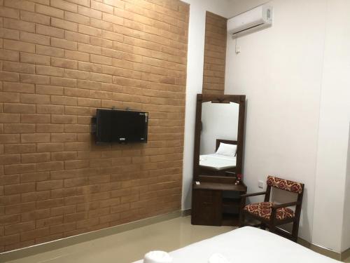 a room with a tv on a brick wall at Hotel Varsha in Kekirawa