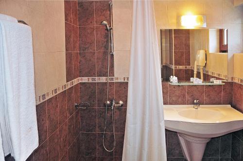 uma casa de banho com um lavatório e um chuveiro com uma cortina de chuveiro em Hotel Real em Plovdiv