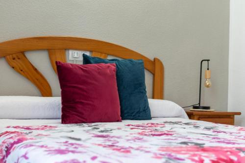 a bed with a wooden headboard and two pillows at Alojamientos Rurales La Hoz in Beteta