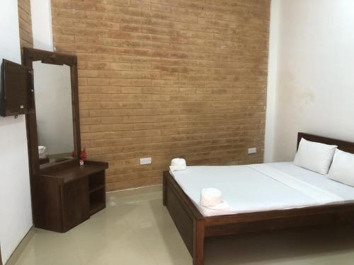 a bedroom with a bed and a mirror and a brick wall at Hotel Varsha in Kekirawa