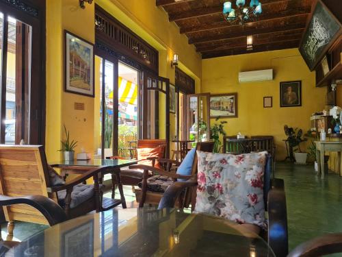 a restaurant with a table and chairs and windows at Sittisang Heritage House 1920 in Kanchanaburi