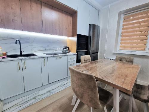a kitchen with a wooden table and a kitchen with white cabinets at Очень уютная квартира рядом с посольством США in Almaty