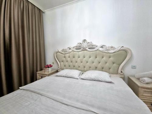 1 dormitorio con cama blanca y cabecero blanco en Очень уютная квартира рядом с посольством США, en Almaty