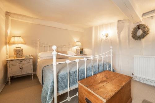 een slaapkamer met een wit bed en een houten kofferbak bij Utterly divine romantic retreat in brilliant village - Tudor Cottage in Sudbury