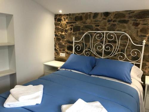 un letto blu in una stanza con un muro in pietra di Casa Cea a Melide