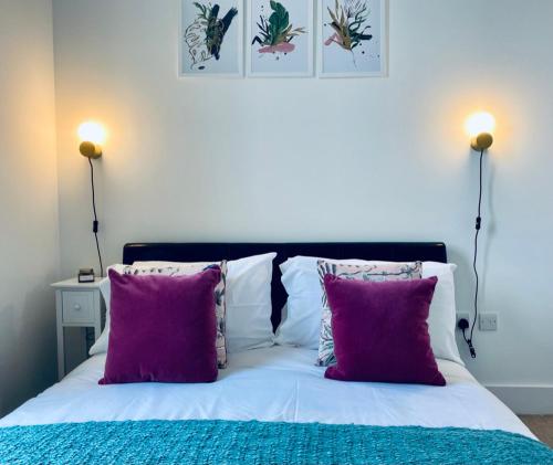 a bed with purple and white pillows and two lamps at Cloud9SA at The Charles Chertsey in Chertsey