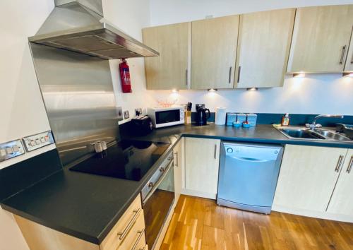 a kitchen with white cabinets and a black counter top at Cloud9SA at The Charles Chertsey in Chertsey