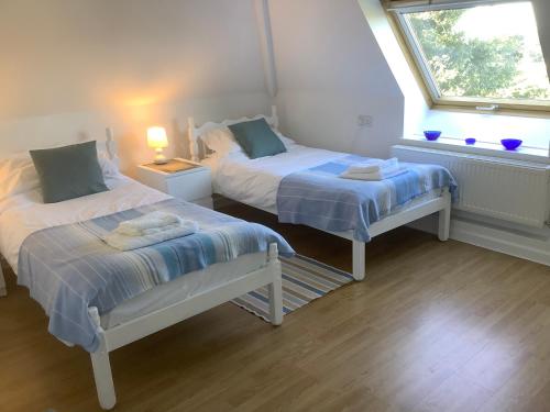 two beds in a small room with a window at Stable Loft in Winscombe