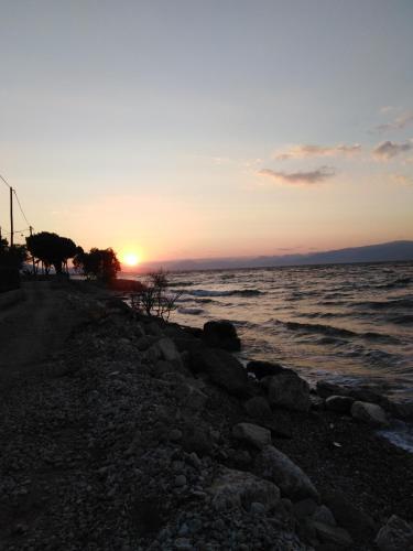 a sunset on the shore of a beach at Σπίτι με σοφίτα μπροστά στη θάλασσα in Trápeza