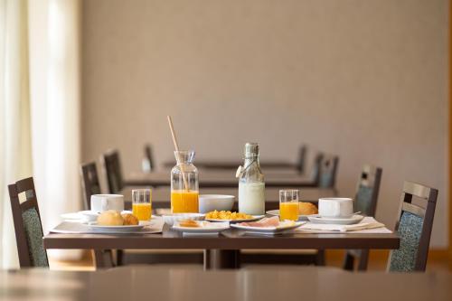 a wooden table with breakfast foods and orange juice at Hotel Rural Vale Do Rio in Oliveira de Azemeis