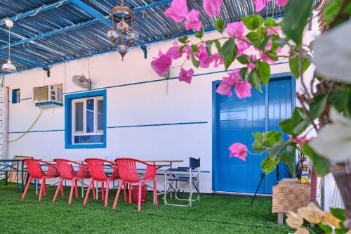 a patio with red chairs and a blue door at Salem Fish Guest House in Al Ḩadd