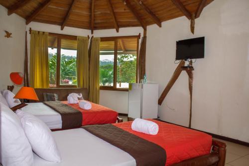1 dormitorio con 2 camas y TV. en Hosteria Orkidea Lodge, en Puyo