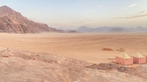 a view of the desert with mountains and buildings at Rum Jordan camp and tours in Wadi Rum