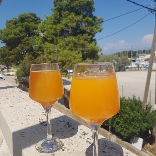 two glasses of orange juice sitting on a ledge at jardin kapetanova kuća in Veli Iž