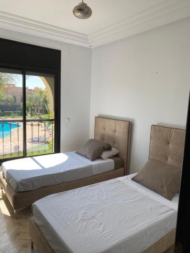 two beds in a bedroom with a view of a pool at Chez balqis atlas golf in Marrakech
