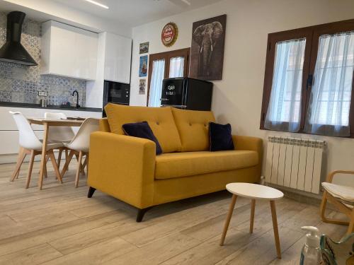 ein Wohnzimmer mit einem gelben Sofa und einer Küche in der Unterkunft El Muro de Piedra in Toledo
