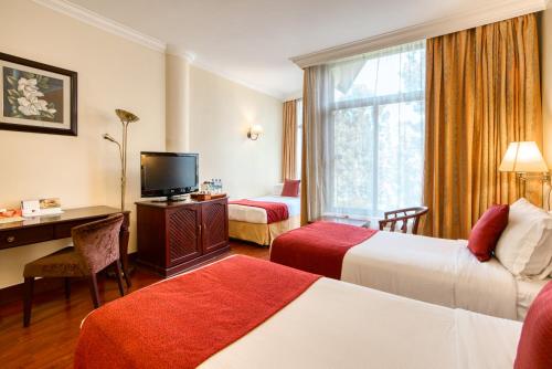a hotel room with two beds and a desk and a television at Kibo Palace Hotel Arusha in Arusha
