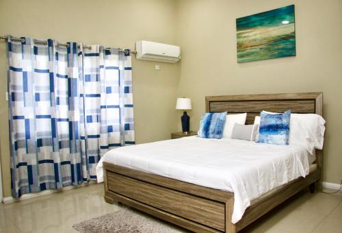 キングストンにあるComfort Homes Jamaicaのベッドルーム1室(青と白のカーテン付きのベッド1台付)