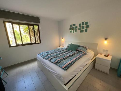 a white bedroom with a bed and a window at Corralejo Happy Place, precioso apartamento con piscina in Corralejo