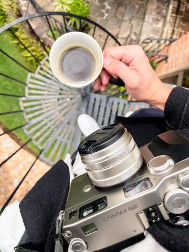 a person holding a cup of coffee next to a camera at Casa Magdalena Hotel Boutique in Morelia