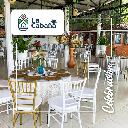 a table with white chairs and a sign in a building at La Cabaña Eco Hotel in Suaita