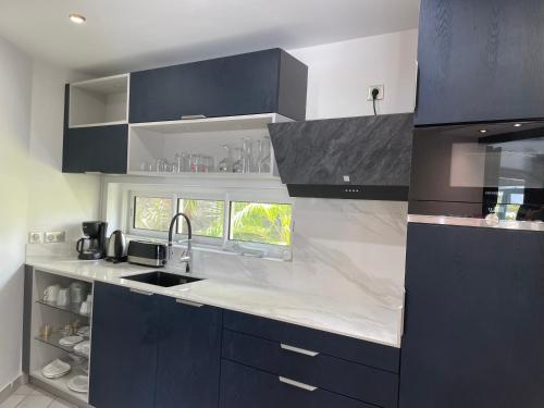 a kitchen with black cabinets and white counter tops at Résidence Adam et Eve in Orient Bay