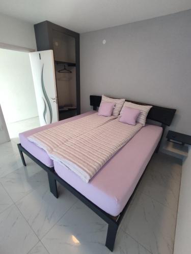 a large bed with pink pillows in a room at Vila ČAROLIJA Futog in Futog