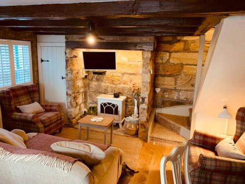 a living room with a couch and a stone wall at Cosy 400 yr old Cottage, Flowergate, Whitby in Whitby