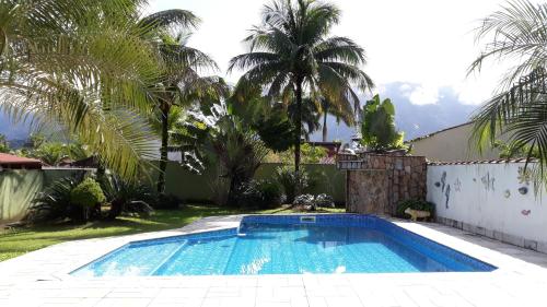 a swimming pool in a yard with palm trees at Morada BEACHE HOUSE 515 in Bertioga