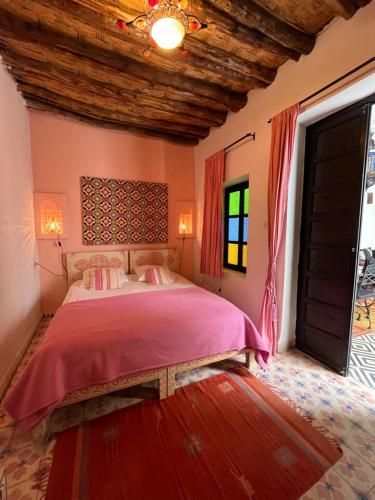 - une chambre avec un lit avec des draps roses et une fenêtre dans l'établissement Riad Miliana, à Marrakech