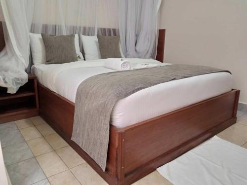 a large bed with a wooden frame in a room at Logmma Regency Hotel in Kakamega