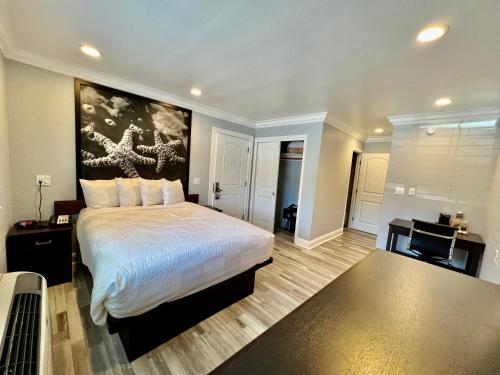 a bedroom with a bed with a painting on the wall at Aura Inn Monterey in Monterey