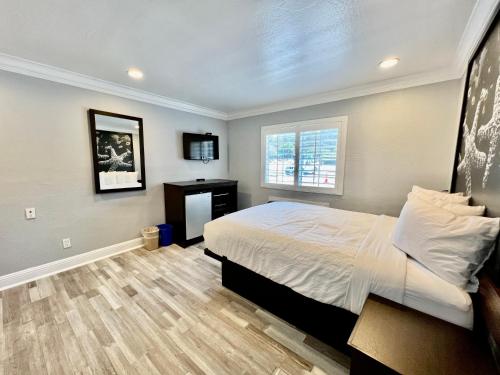 a bedroom with a bed and a desk and a window at Aura Inn Monterey in Monterey