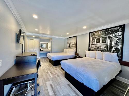 a hotel room with two beds and a desk at Aura Inn Monterey in Monterey