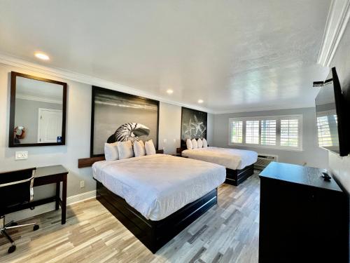 a bedroom with two beds and a flat screen tv at Aura Inn Monterey in Monterey