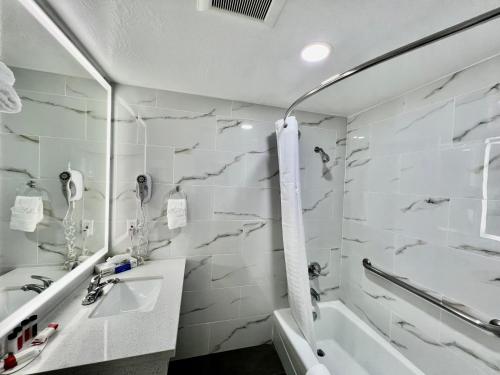 a white bathroom with a sink and a tub at Aura Inn Monterey in Monterey