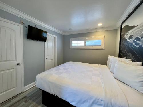 a bedroom with a bed with a tv on the wall at Aura Inn Monterey in Monterey