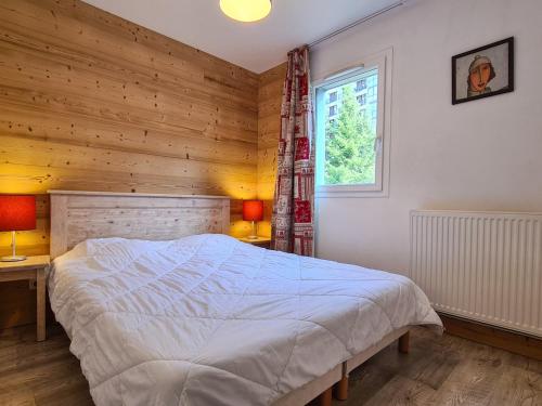 - une chambre avec un lit et un mur en bois dans l'établissement Spacieux Appartement 3 Pièces + Cabine à Flaine Forêt, Balcon & Parking - FR-1-425-134, à Flaine
