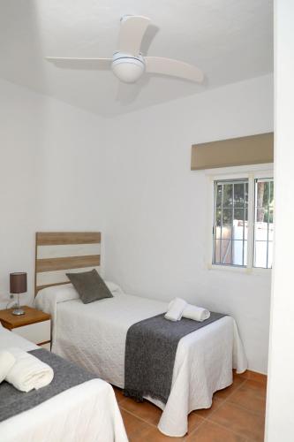 a bedroom with two beds and a ceiling fan at Casa La Herradura 1 in Vejer de la Frontera
