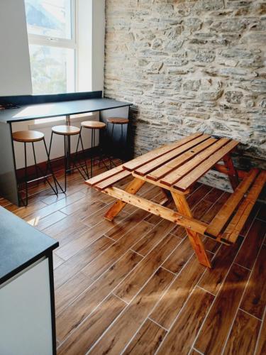 a wooden picnic table in a room with a stone wall at Voyage Hostel - Ensuite Family Rooms with shared kitchen in Douglas