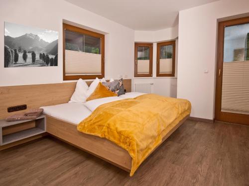 Un dormitorio con una cama grande con una manta amarilla. en Landhaus Sabrina, en Mayrhofen