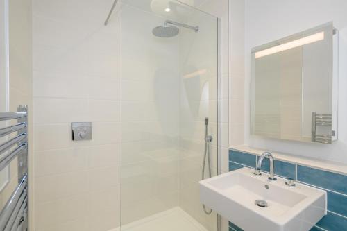 Un baño blanco con lavabo y ducha. en 6 Challacombe - Luxury Apartment at Byron Woolacombe, only 4 minute walk to Woolacombe Beach!, en Woolacombe