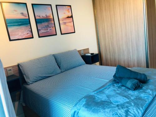 a bedroom with a blue bed with pictures on the wall at Makambira Residence By SummerFlats no CENTRO DE PORTO DE GALINHAS in Porto De Galinhas