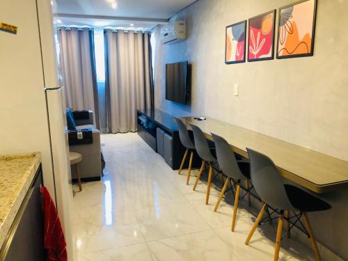 une chambre avec des chaises, une table et une télévision dans l'établissement Makambira Residence By SummerFlats no CENTRO DE PORTO DE GALINHAS, à Porto de Galinhas