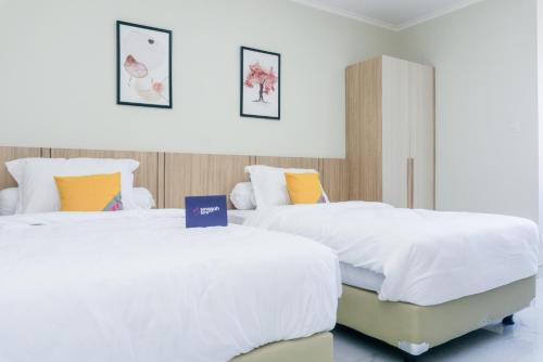 2 camas en una habitación de hotel con sábanas blancas en Singgahsini Rungkut Syariah, en Medokanayu
