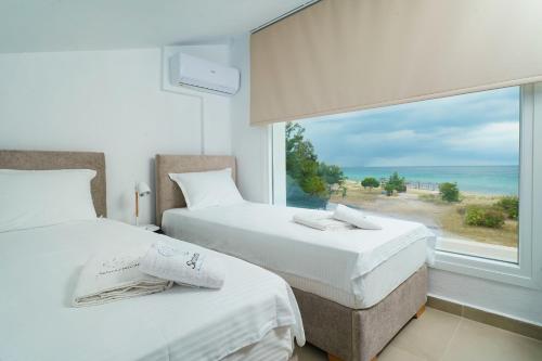 two beds in a room with a view of the ocean at Sentimento Sea Breeze in Skala Prinou