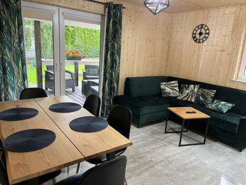 a living room with two tables and a green couch at Jantar Domki Comfort oraz Comfort Wellness Zone sauna jacuzzi in Jantar